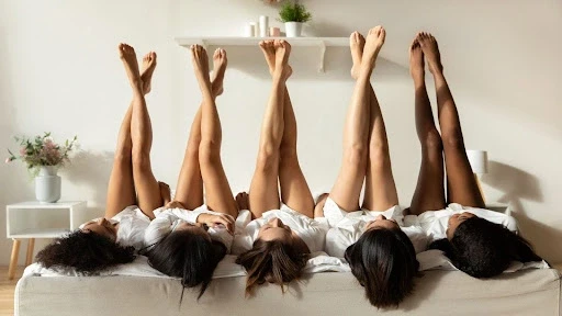 Cinq femmes allongées, les jambes en l'air qui se croisent