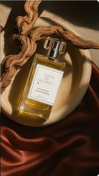 Une bouteille de parfum associé à du bois, déposée sur un tissu de soie